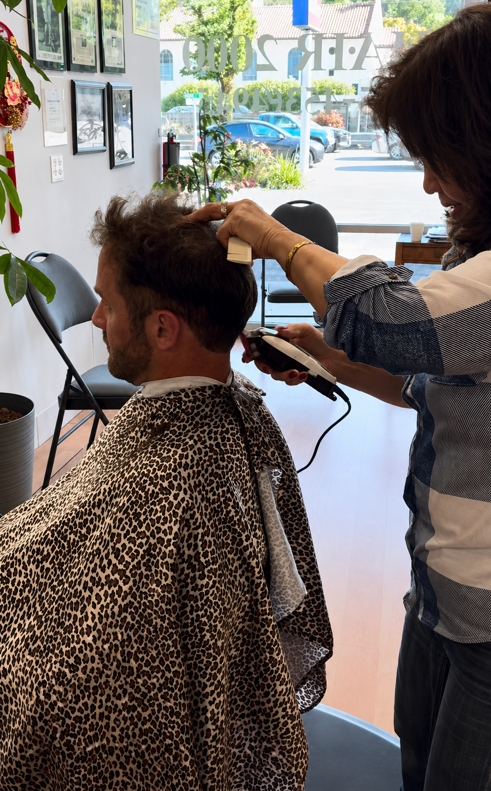 Hair 2000 stylist trimming a client near the front window